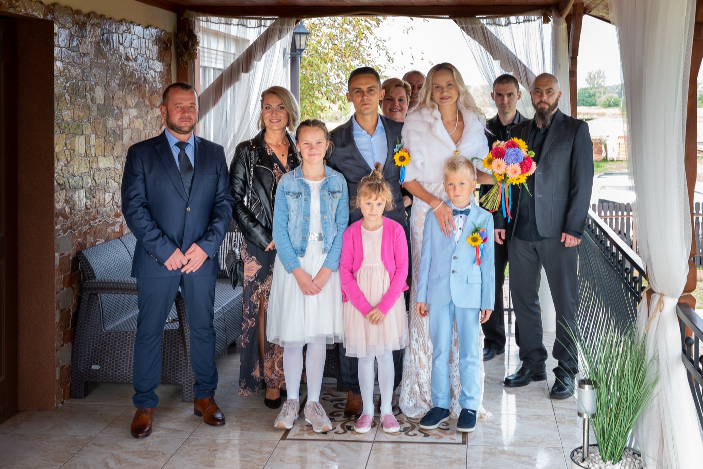 Państwo młodzi z rodziną na ganku, przed wejściem na ceremonię.