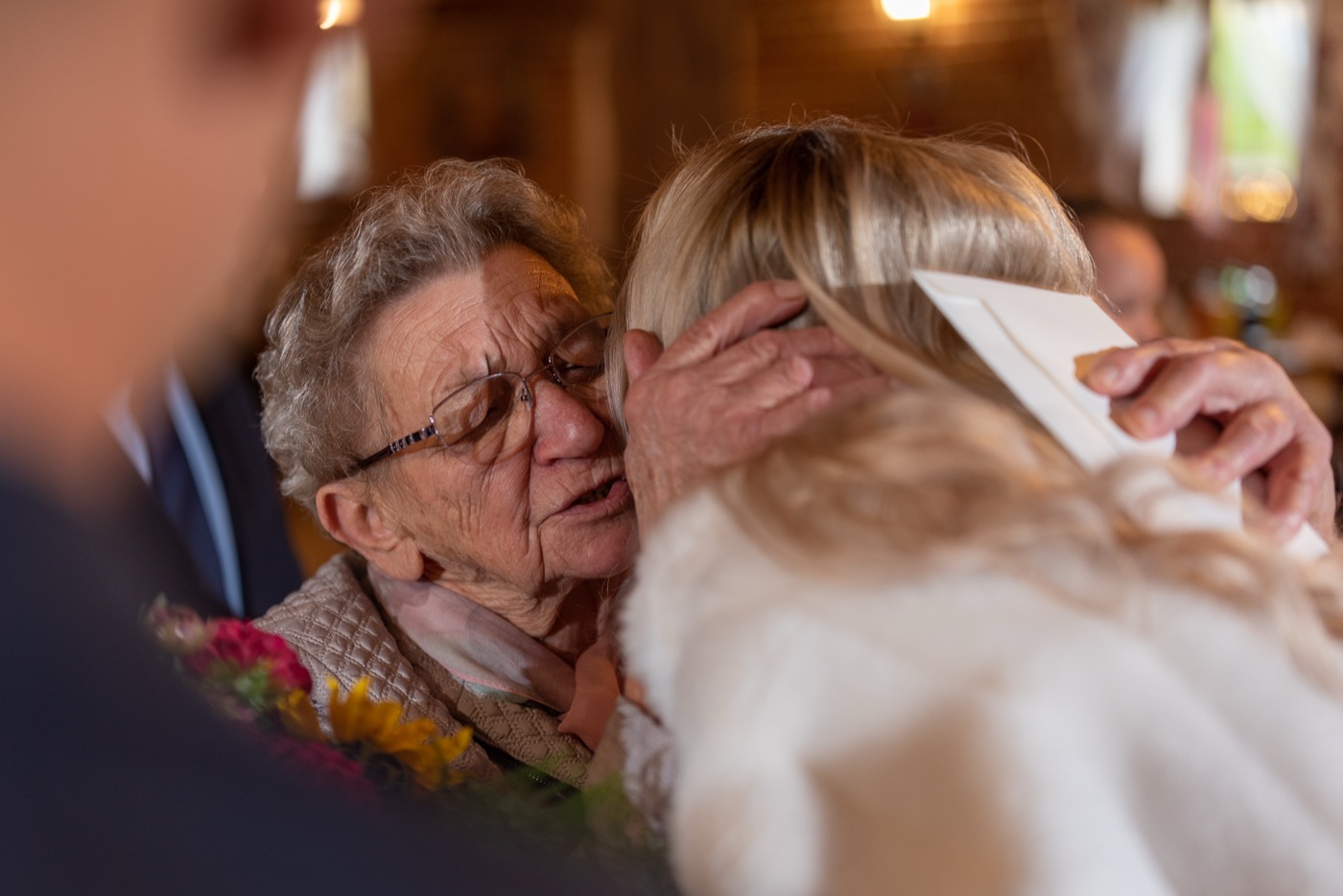 Babcia obejmuje pannę młodą, wręczając kopertę z prezentem.