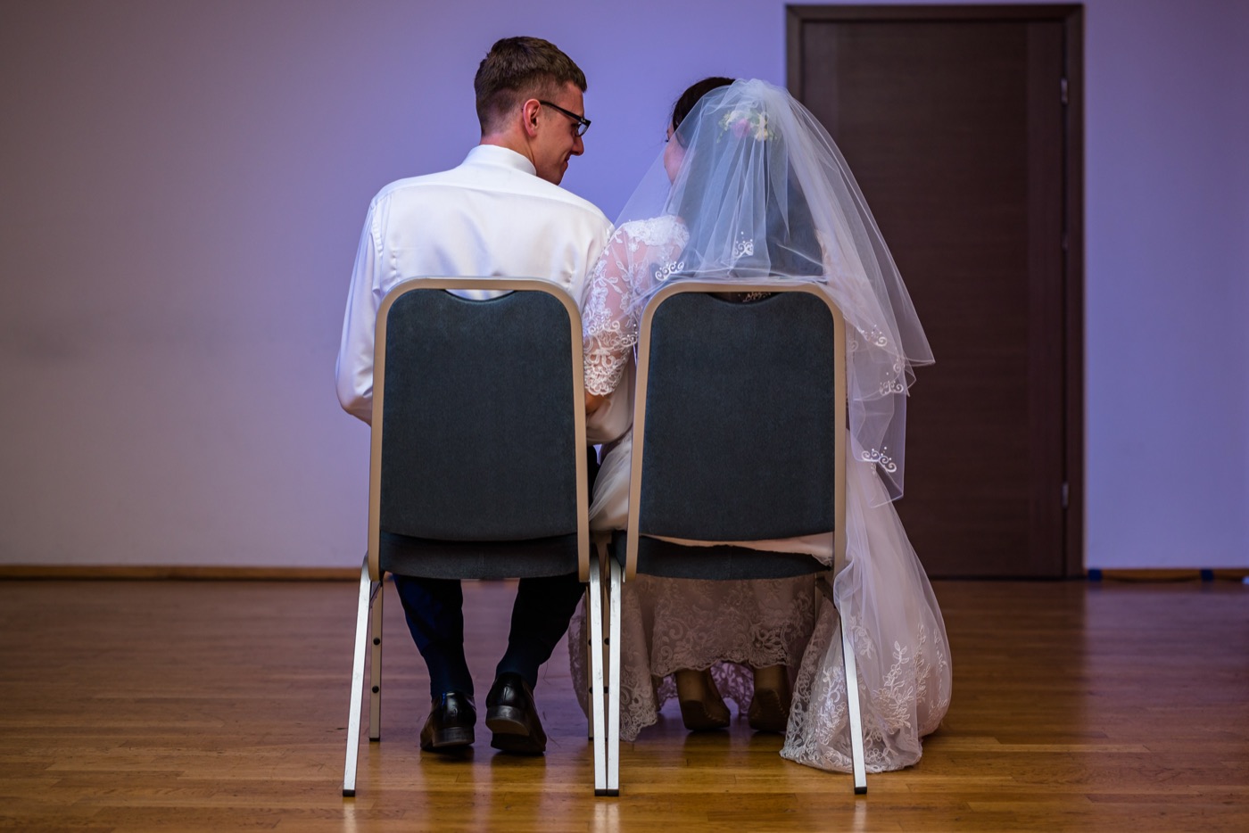 Państwo młodzi siedzą tyłem do obiektywu.